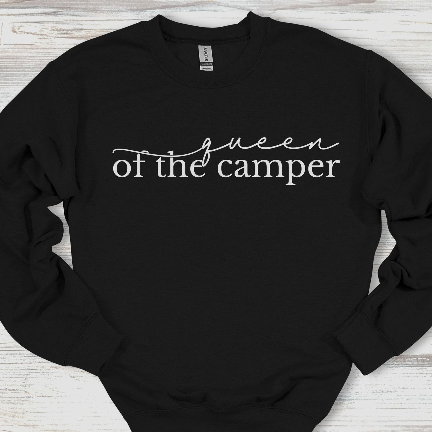 Black sweatshirt with 'queen of the camper' text on a wooden surface