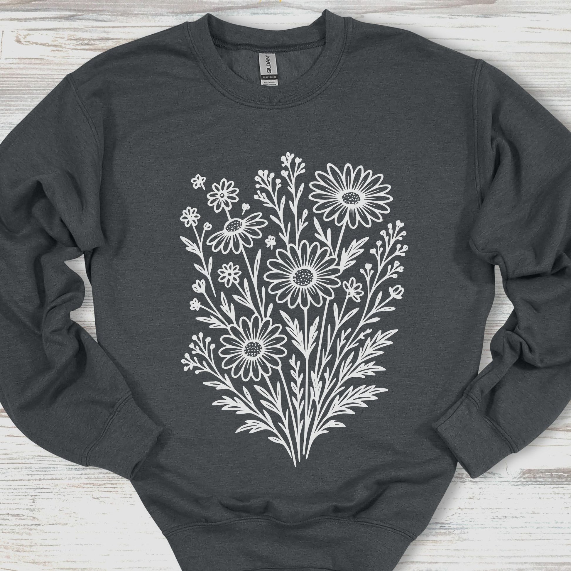 Dark gray sweatshirt with white floral heart design on a wooden surface