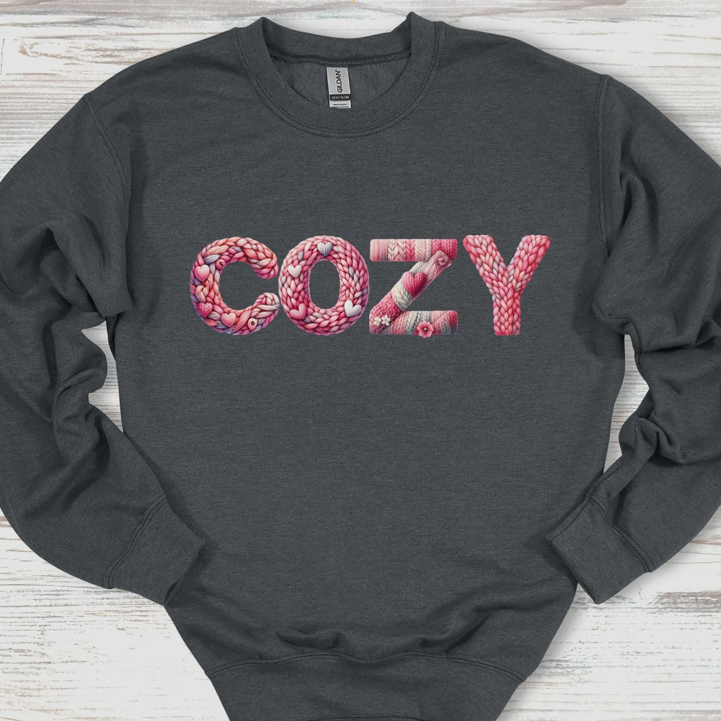 Dark gray sweatshirt with 'COZY' in pink text on a wooden surface