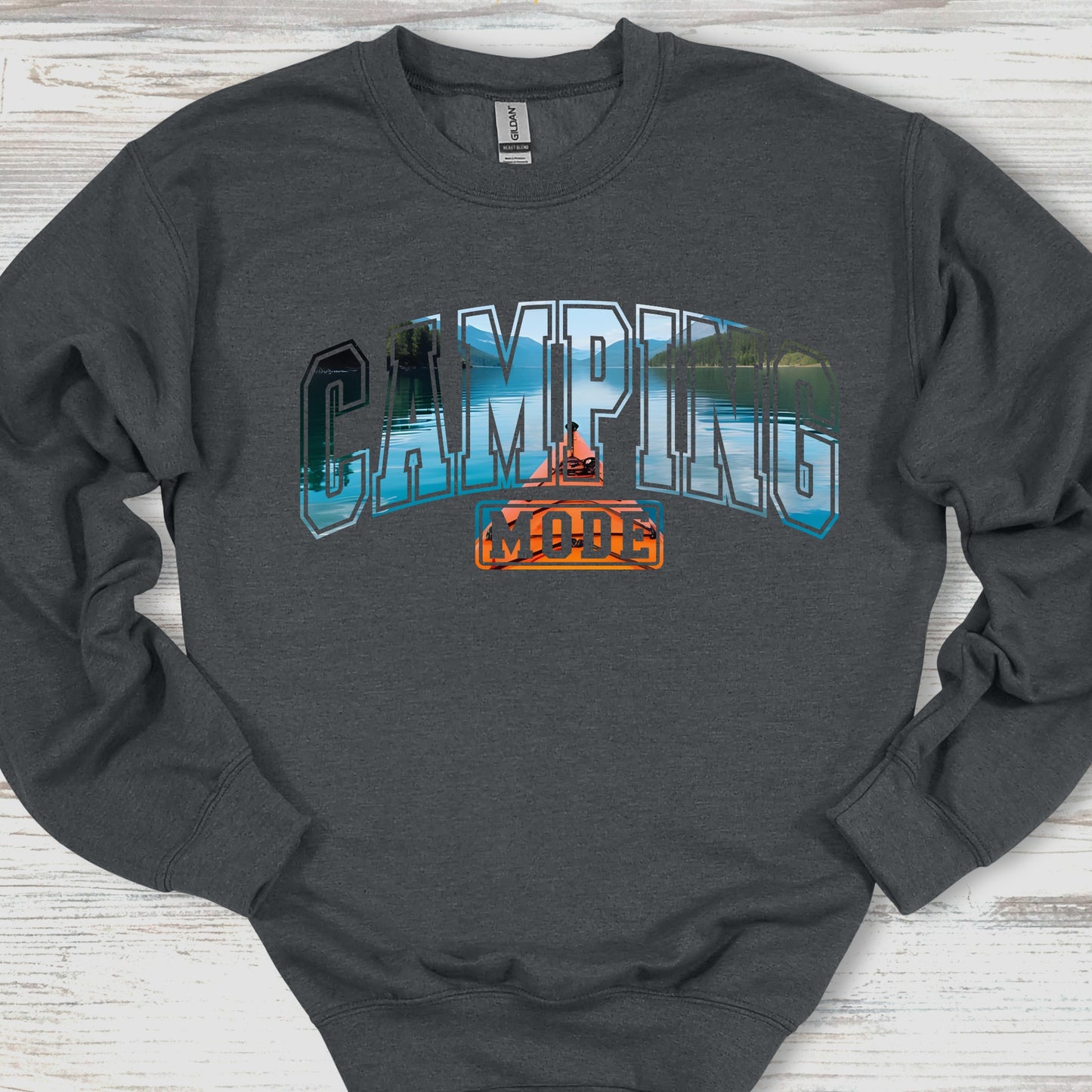 Dark gray sweatshirt with 'Camping is Cool' graphic on a wooden surface