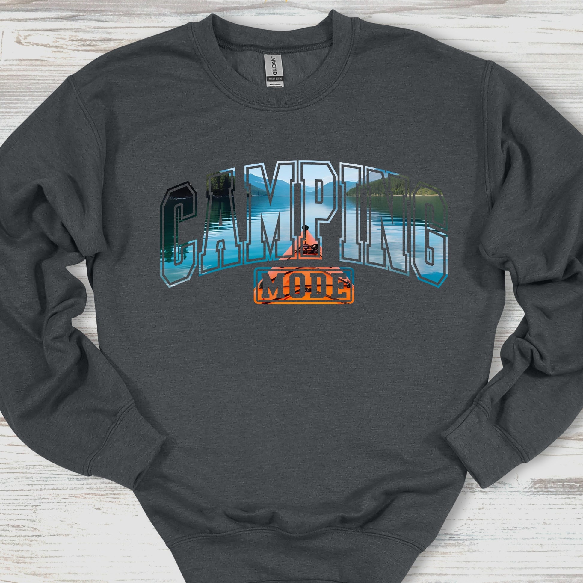 Dark gray sweatshirt with 'Camping is Cool' graphic on a wooden surface