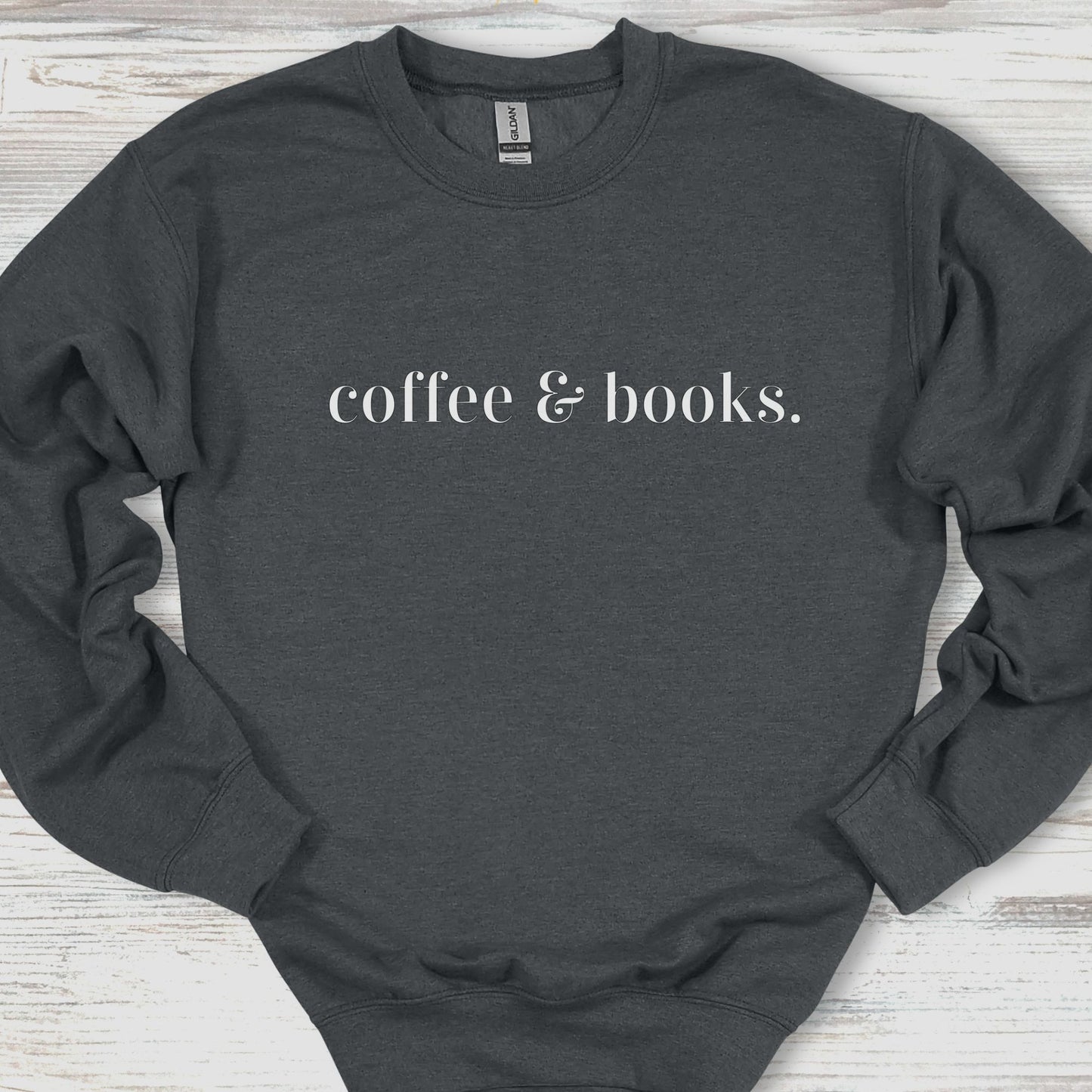 Dark gray sweatshirt with 'coffee & books.' text on a wooden surface