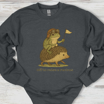 Dark gray sweatshirt with a graphic of a frog and hedgehog riding together, holding a flag, on a wooden surface.