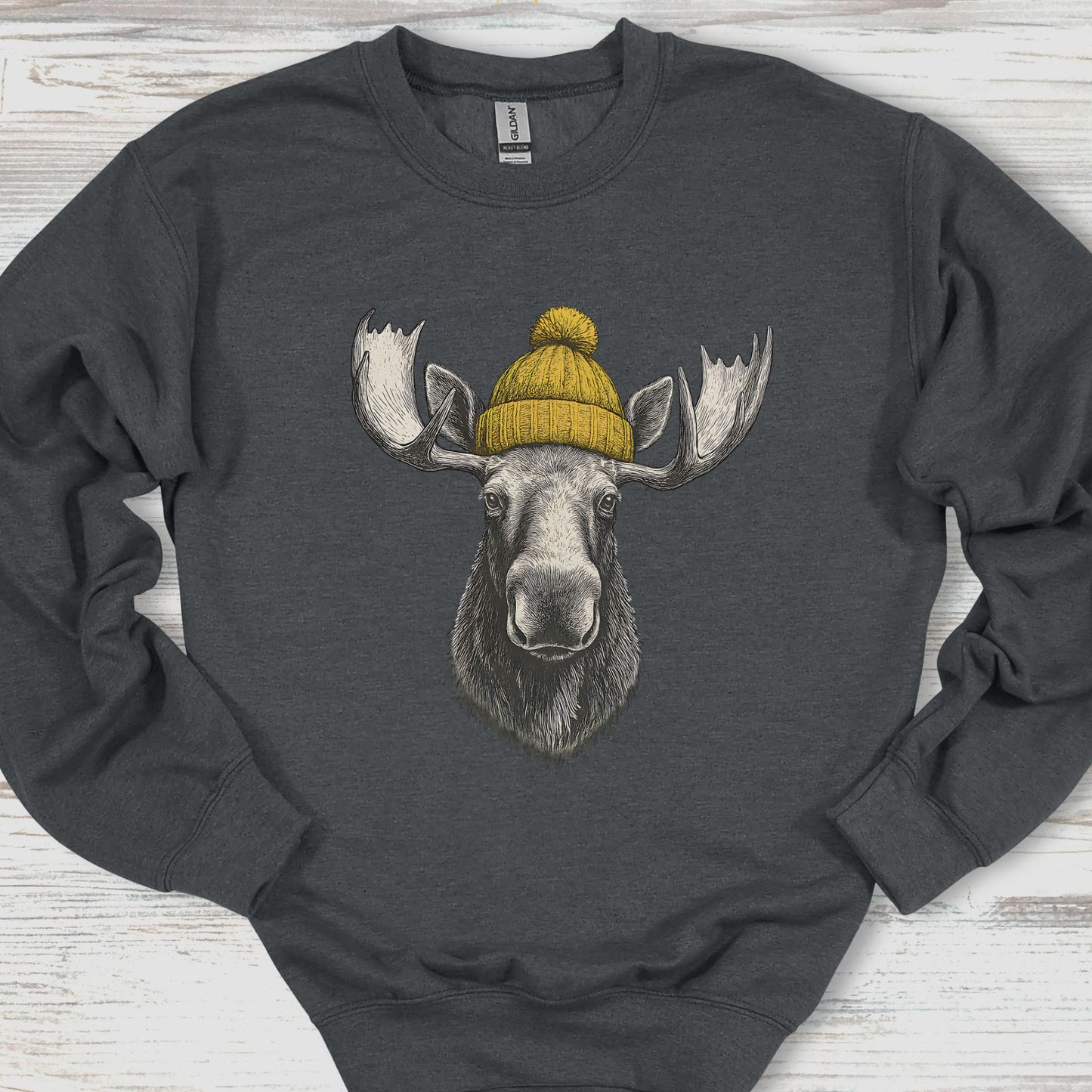 Gray sweatshirt with a moose wearing a yellow beanie on a wooden surface