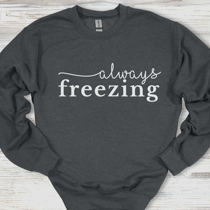 Dark gray sweatshirt with 'always freezing' text on a wooden surface