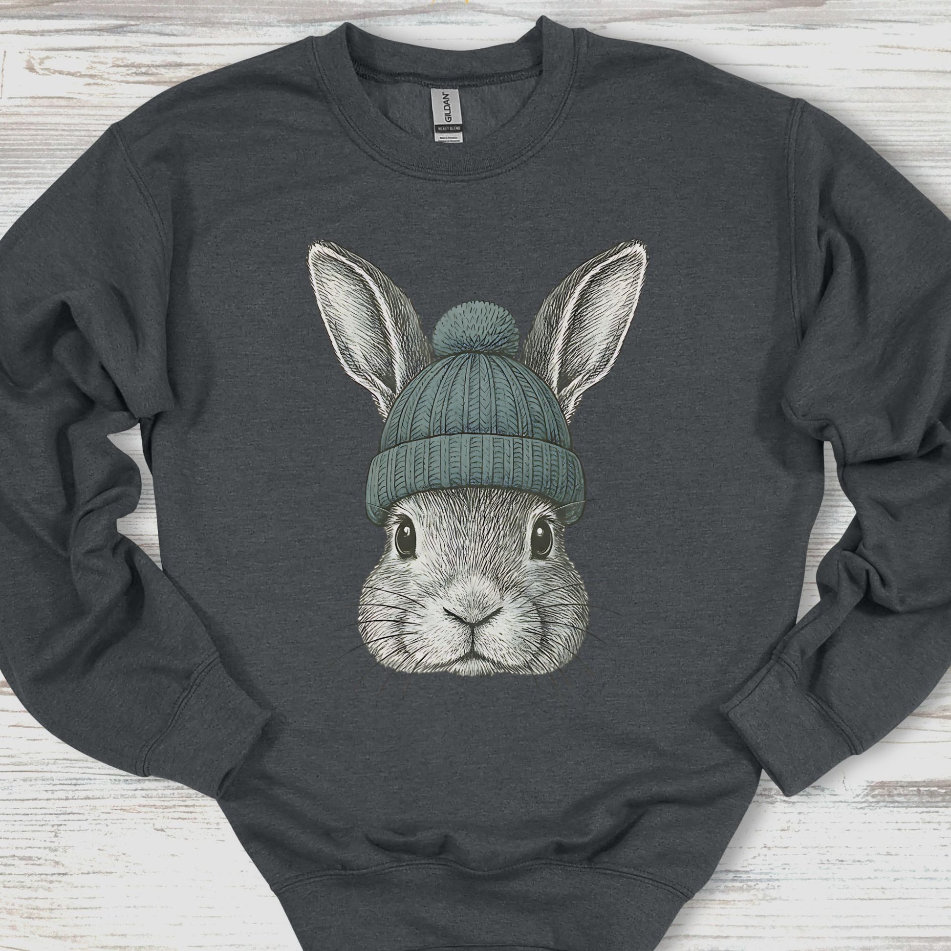 Dark gray sweatshirt with a graphic of a rabbit wearing a green beanie on a wooden surface.