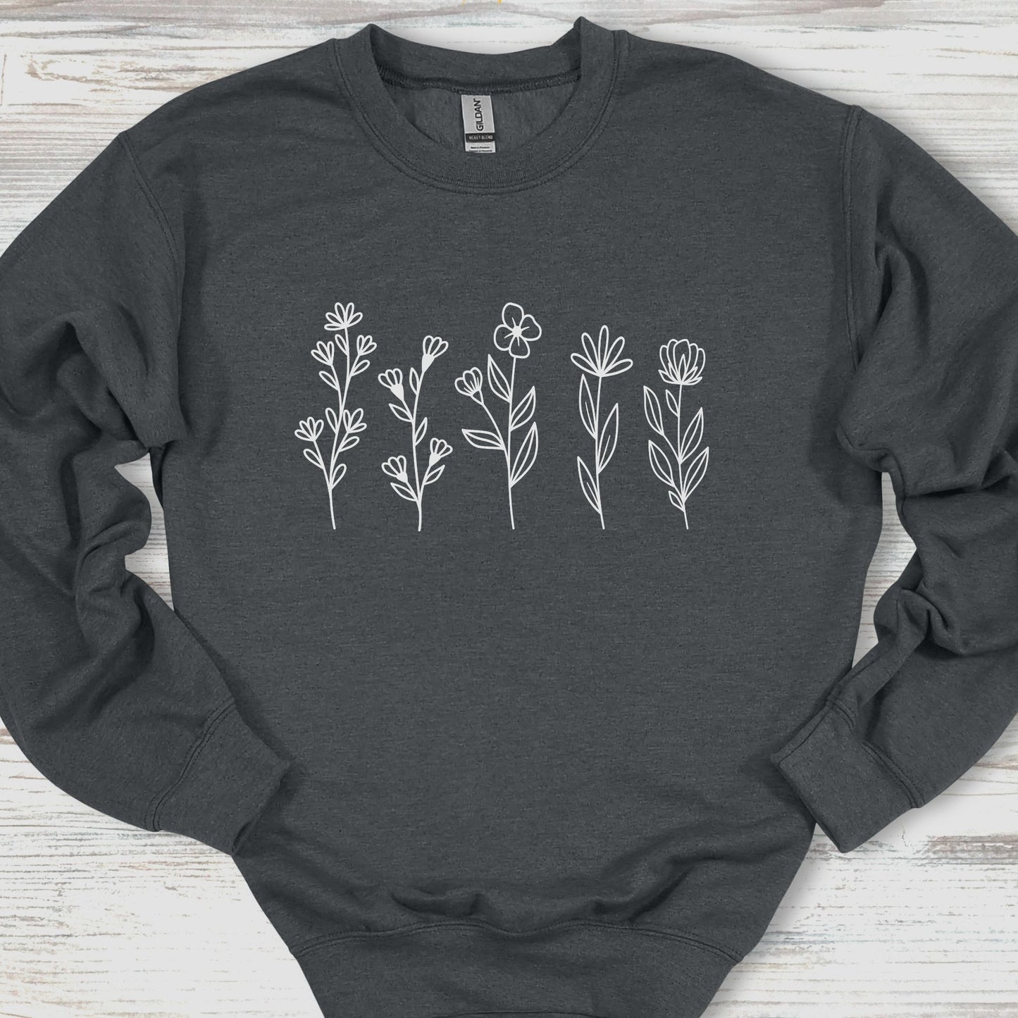 Dark gray sweatshirt with white floral designs on a wooden surface