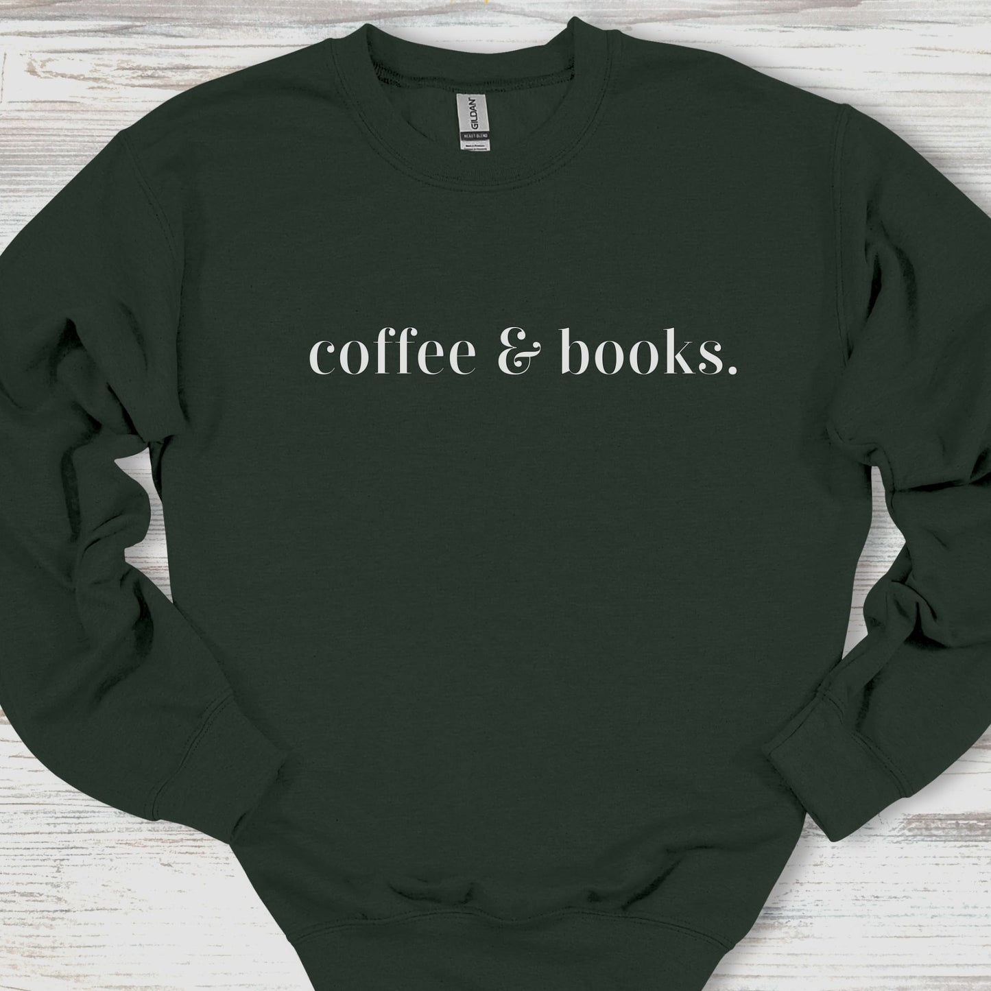 Black sweatshirt with 'coffee & books.' text on a wooden surface