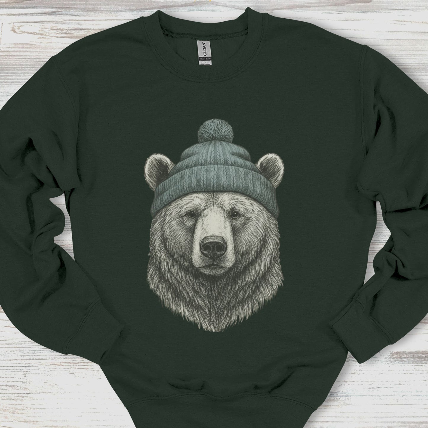 Black sweatshirt with a bear wearing a green beanie on a wooden surface