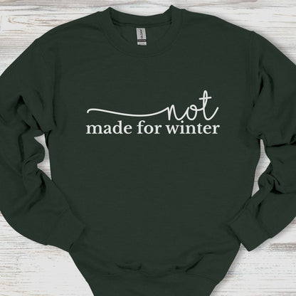 Black sweatshirt with 'not made for winter' text on a wooden surface