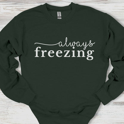 Black sweatshirt with 'always freezing' text on a wooden surface