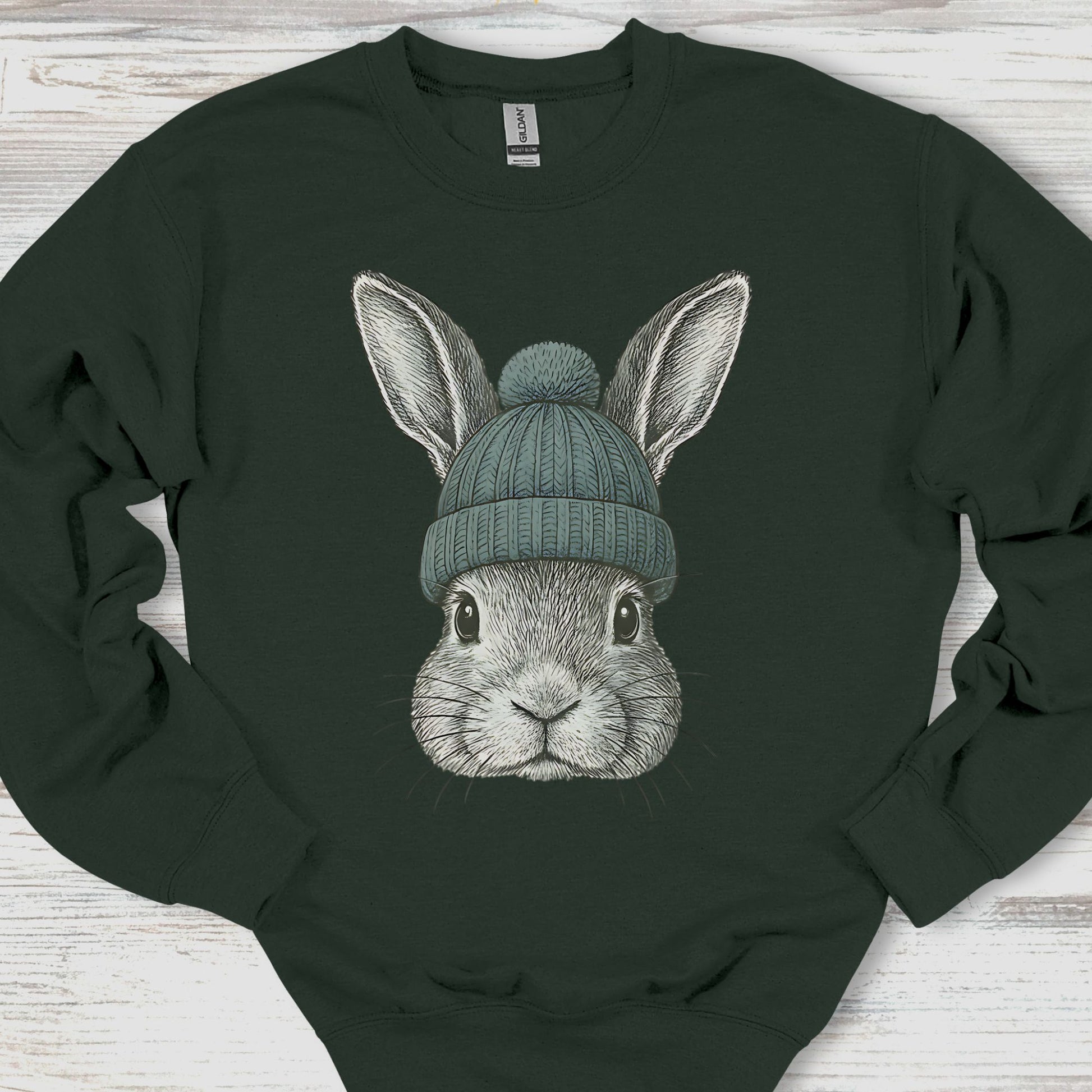 Dark green sweatshirt with a rabbit wearing a beanie on a wooden surface