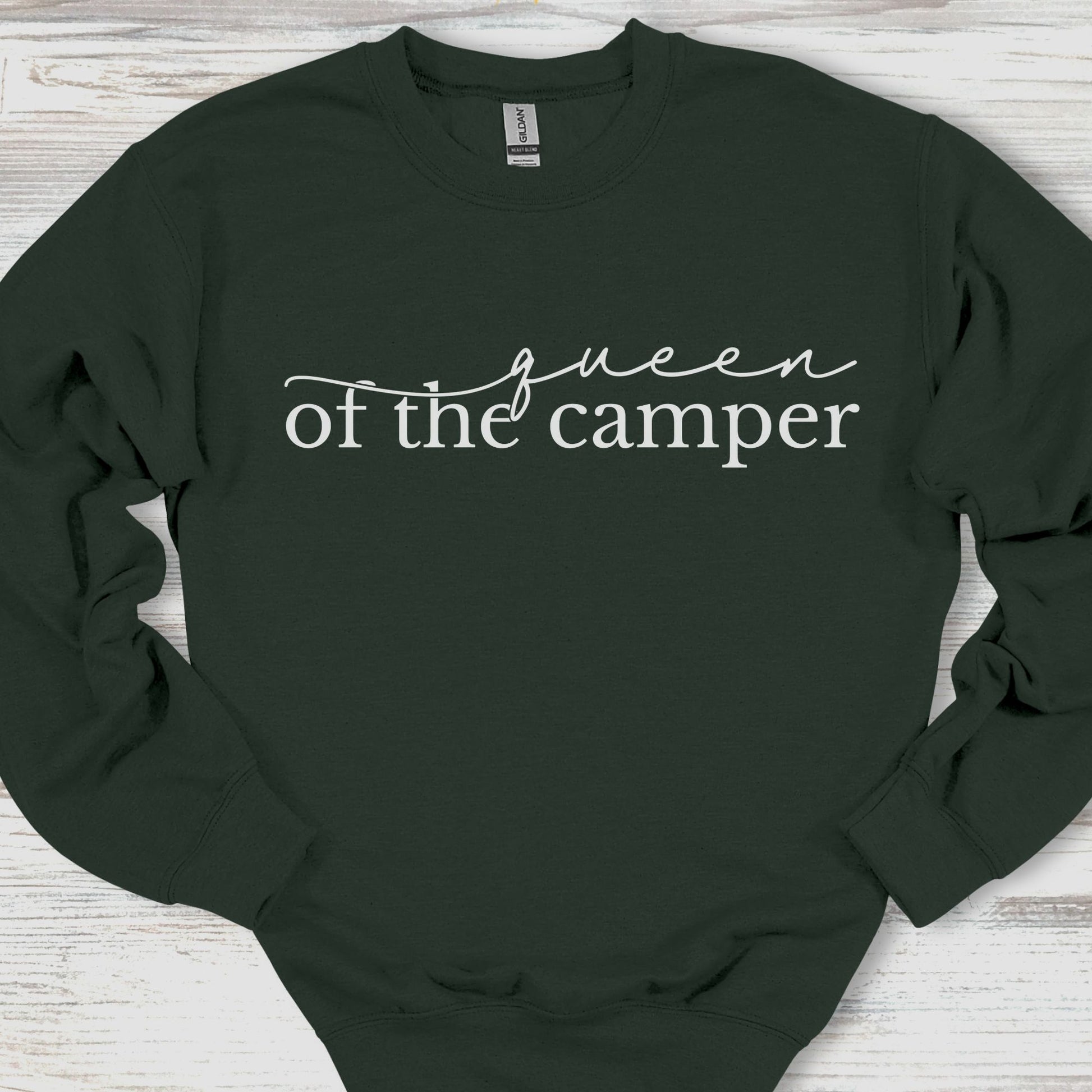 Black sweatshirt with 'queen of the camper' text on a wooden surface