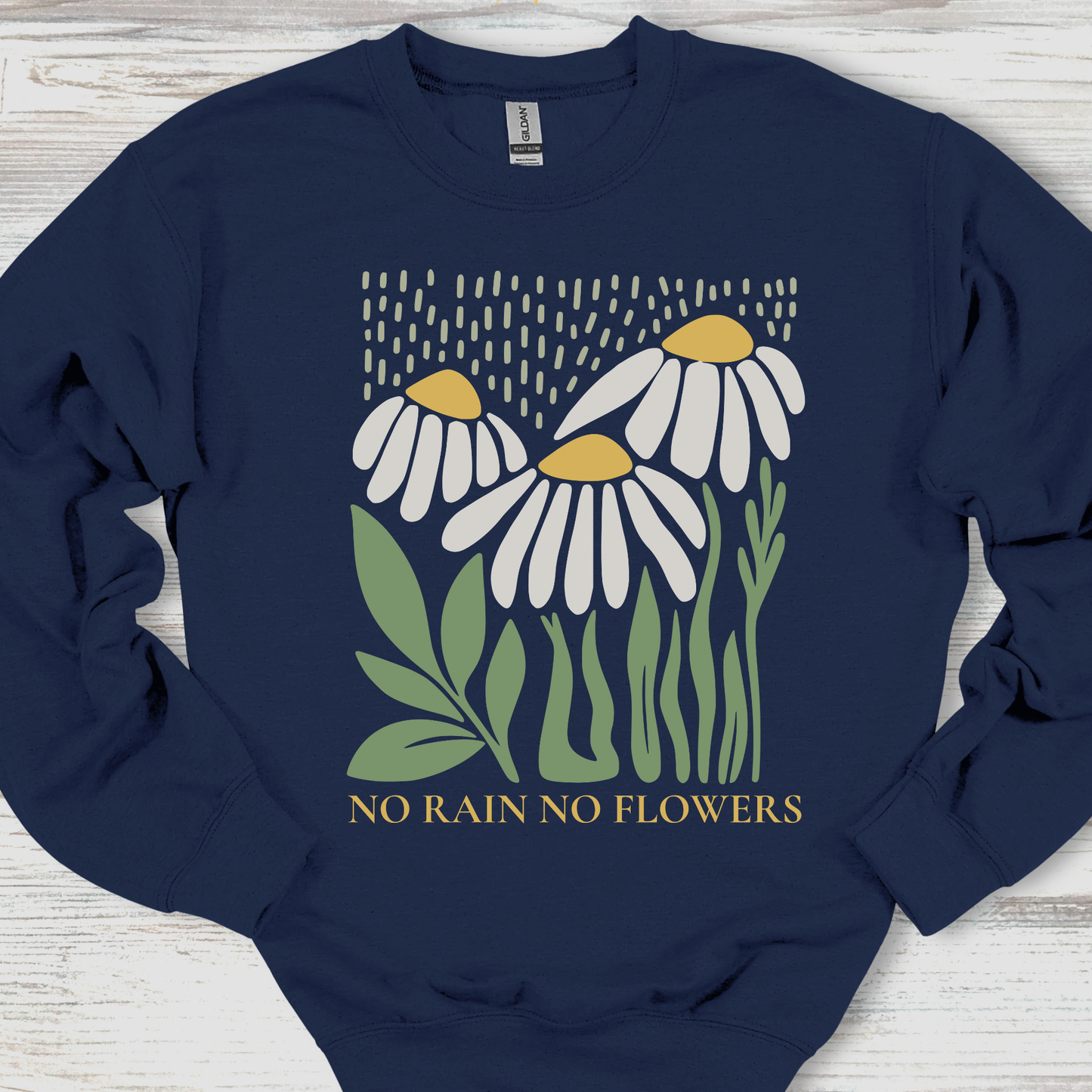 Navy blue sweatshirt with floral design and 'No Rain No Flowers' text on a wooden surface