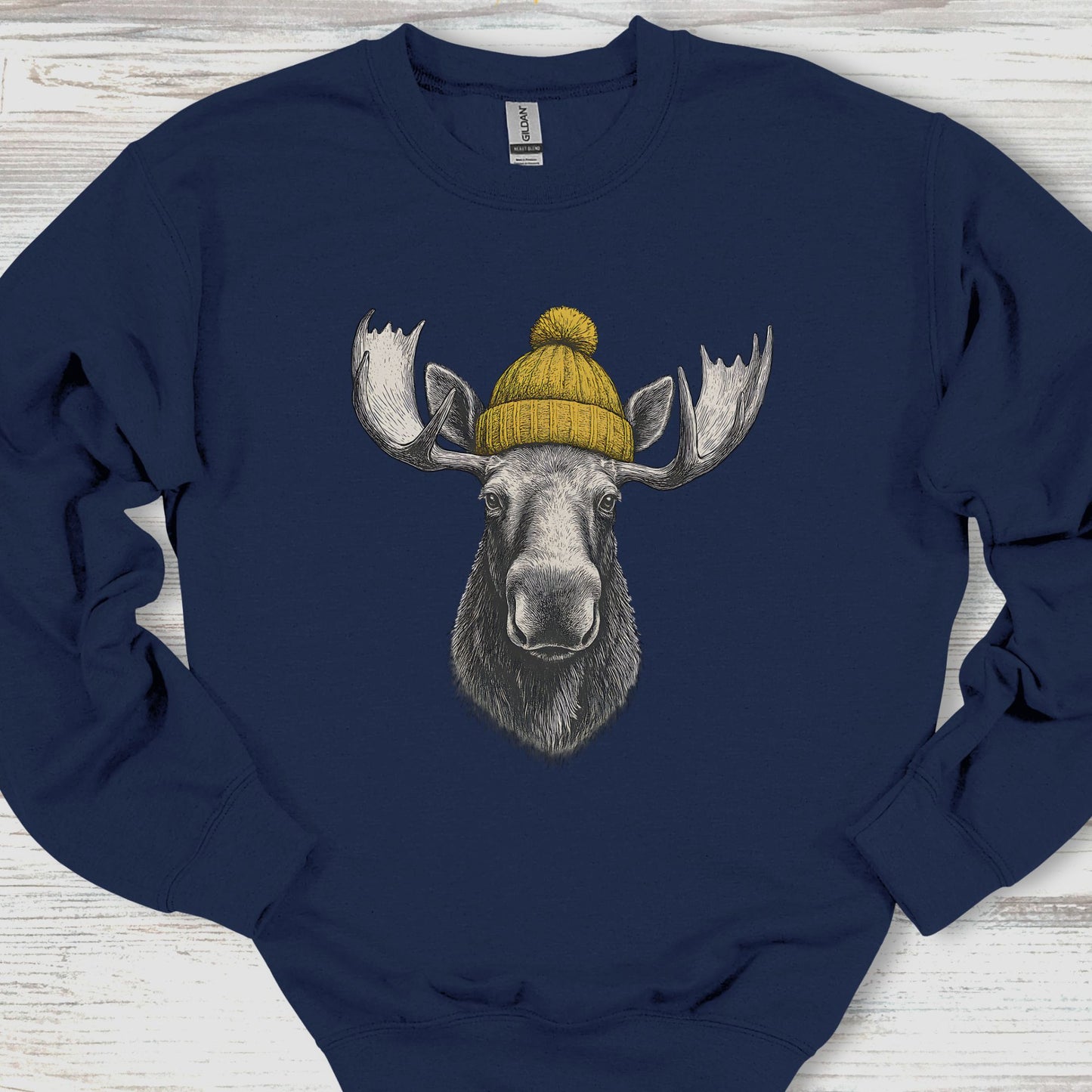 Navy blue sweatshirt with a moose wearing a yellow beanie on a wooden surface