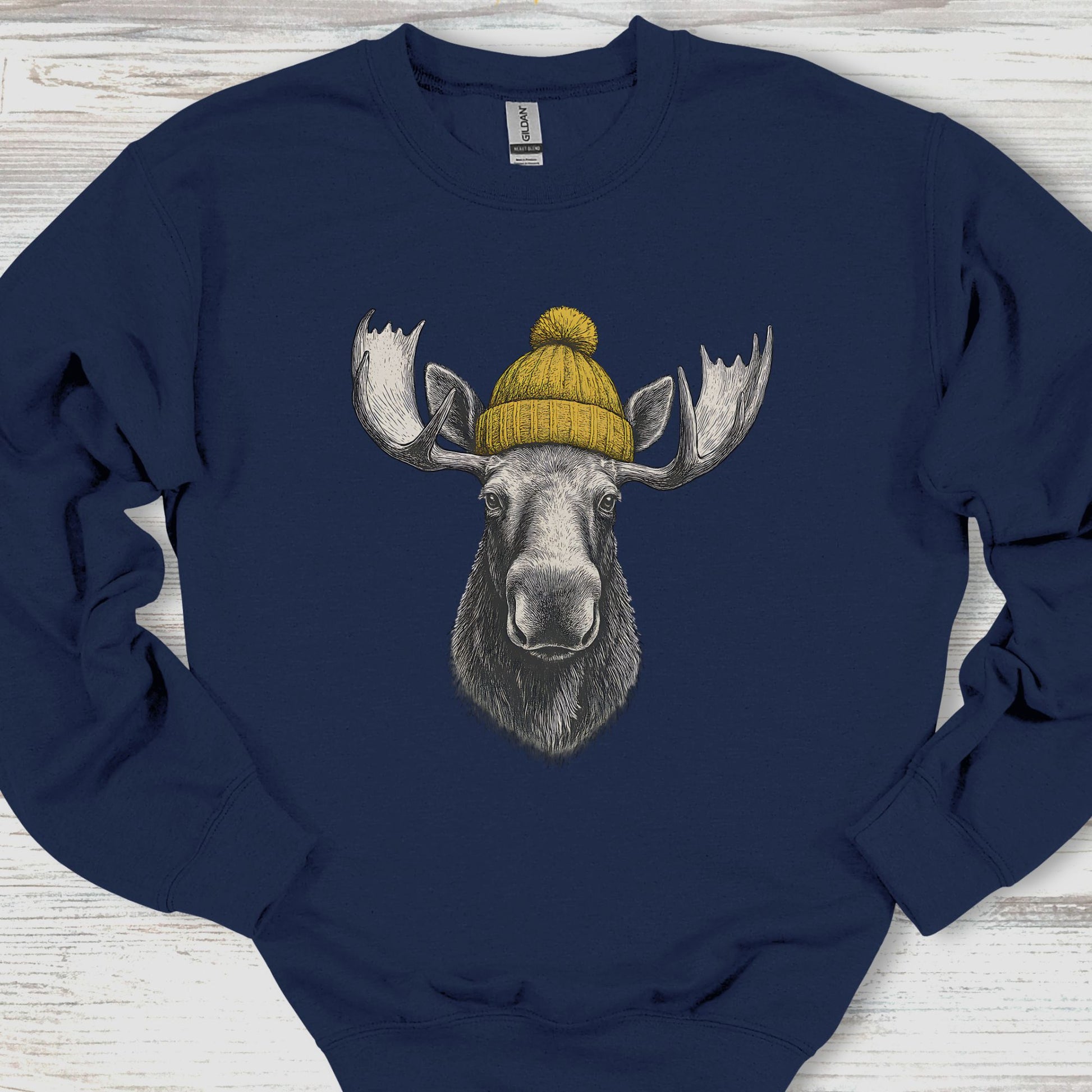 Navy blue sweatshirt with a moose wearing a yellow beanie on a wooden surface