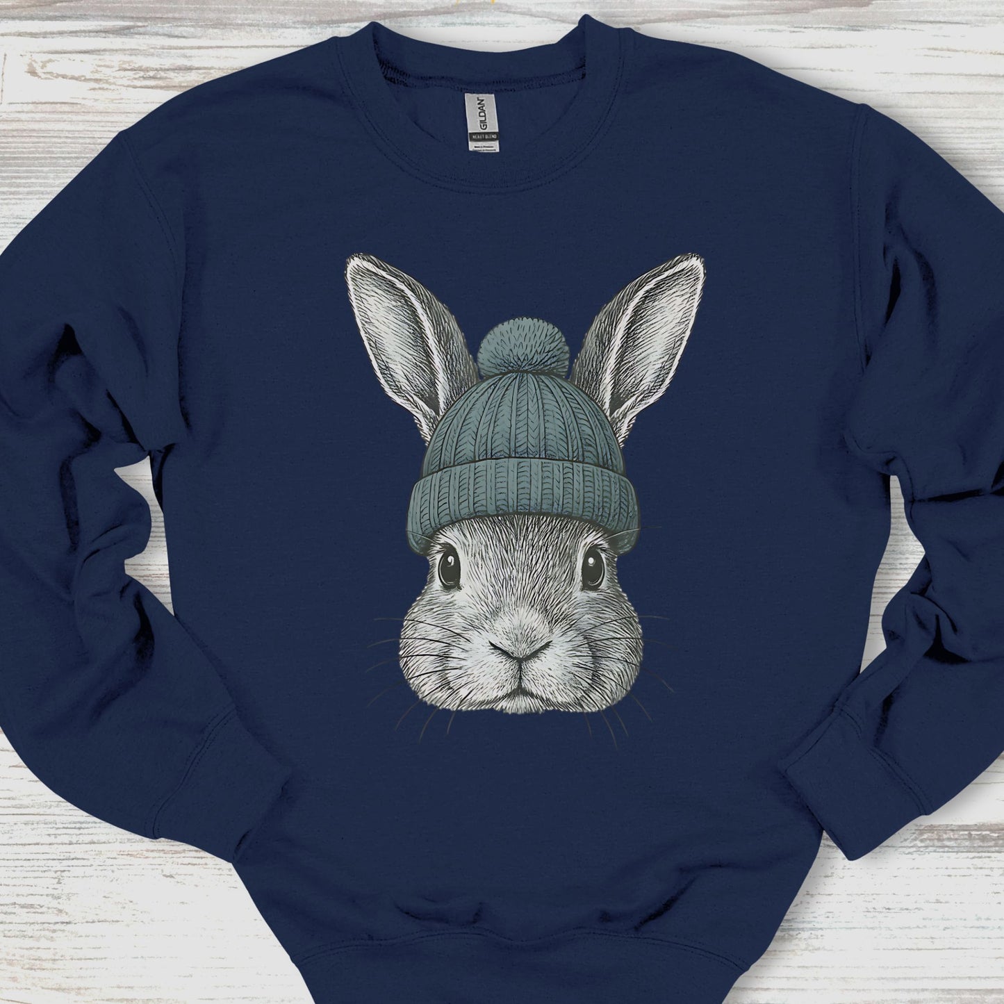 Navy blue sweatshirt with a graphic of a rabbit wearing a green beanie on a wooden surface.