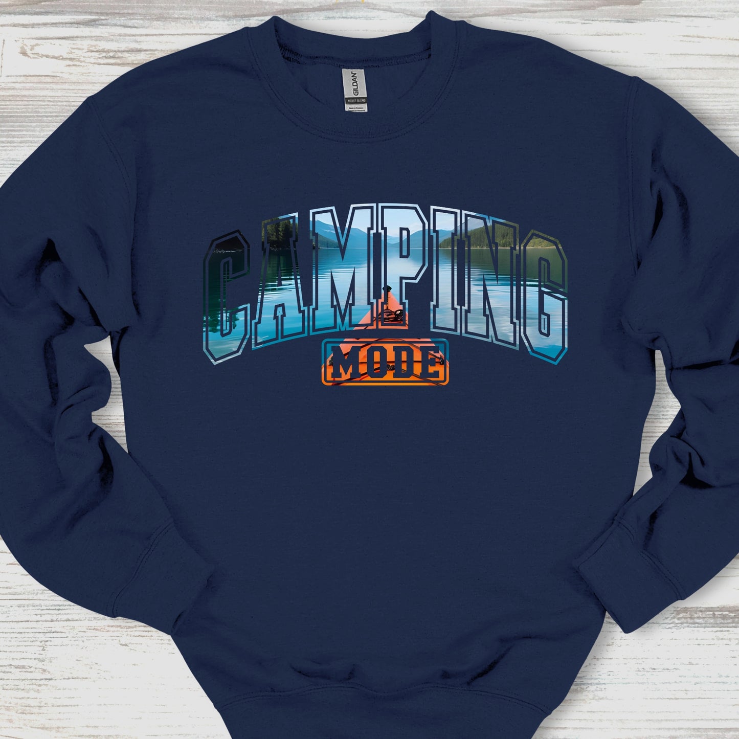 Navy blue sweatshirt with 'Camping Mode' graphic on a wooden surface