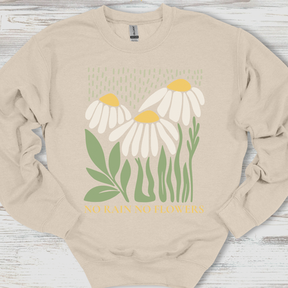 Beige sweatshirt with daisy flower design and text on a wooden surface