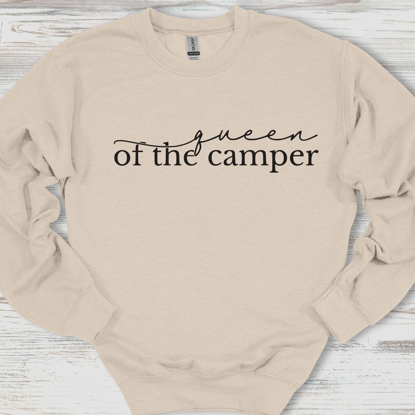 Beige sweatshirt with 'Queen of the Camper' text on a wooden surface