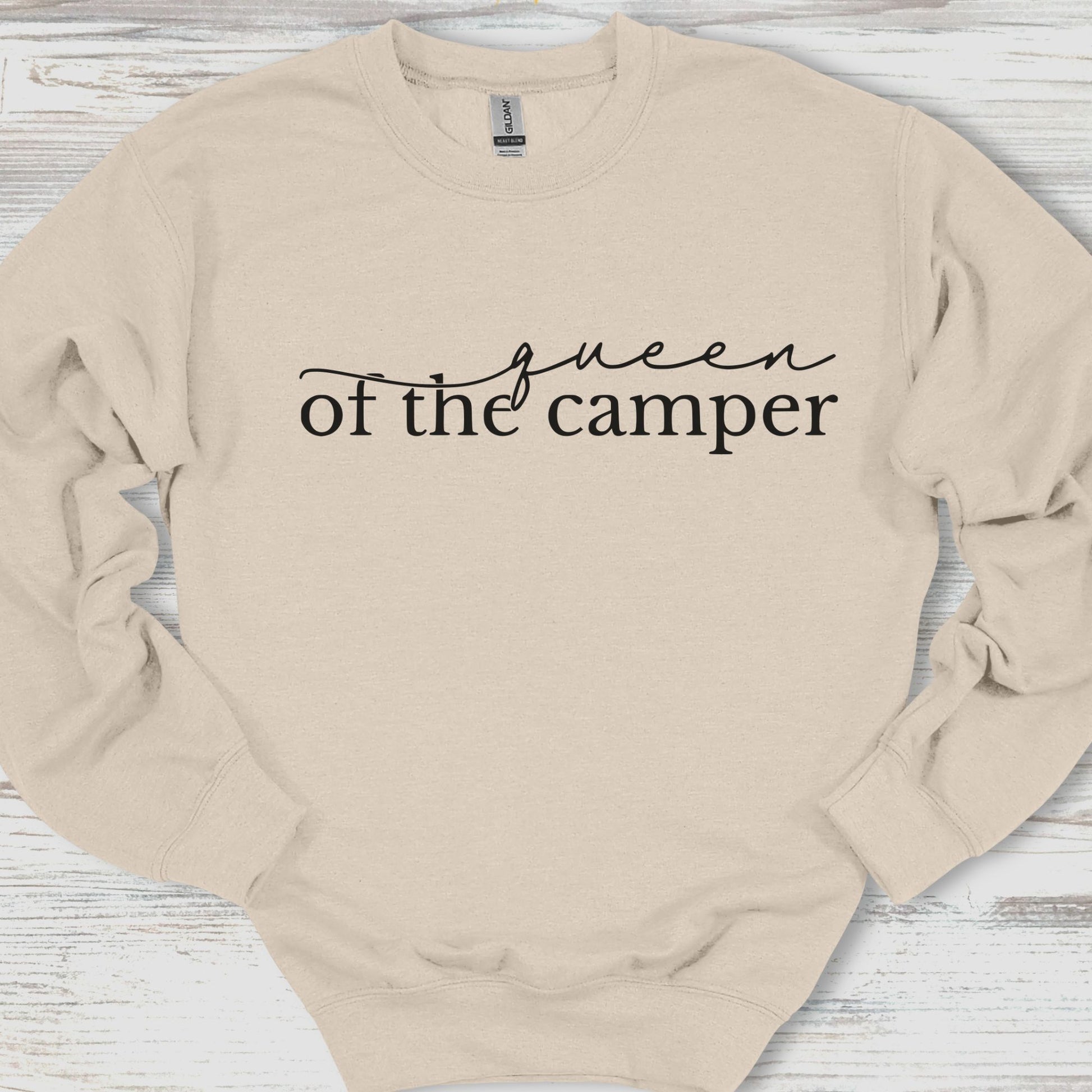 Beige sweatshirt with 'Queen of the Camper' text on a wooden surface