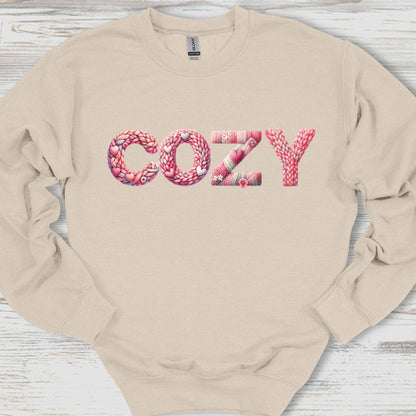 Beige sweatshirt with 'COZY' printed in pink letters on a wooden surface