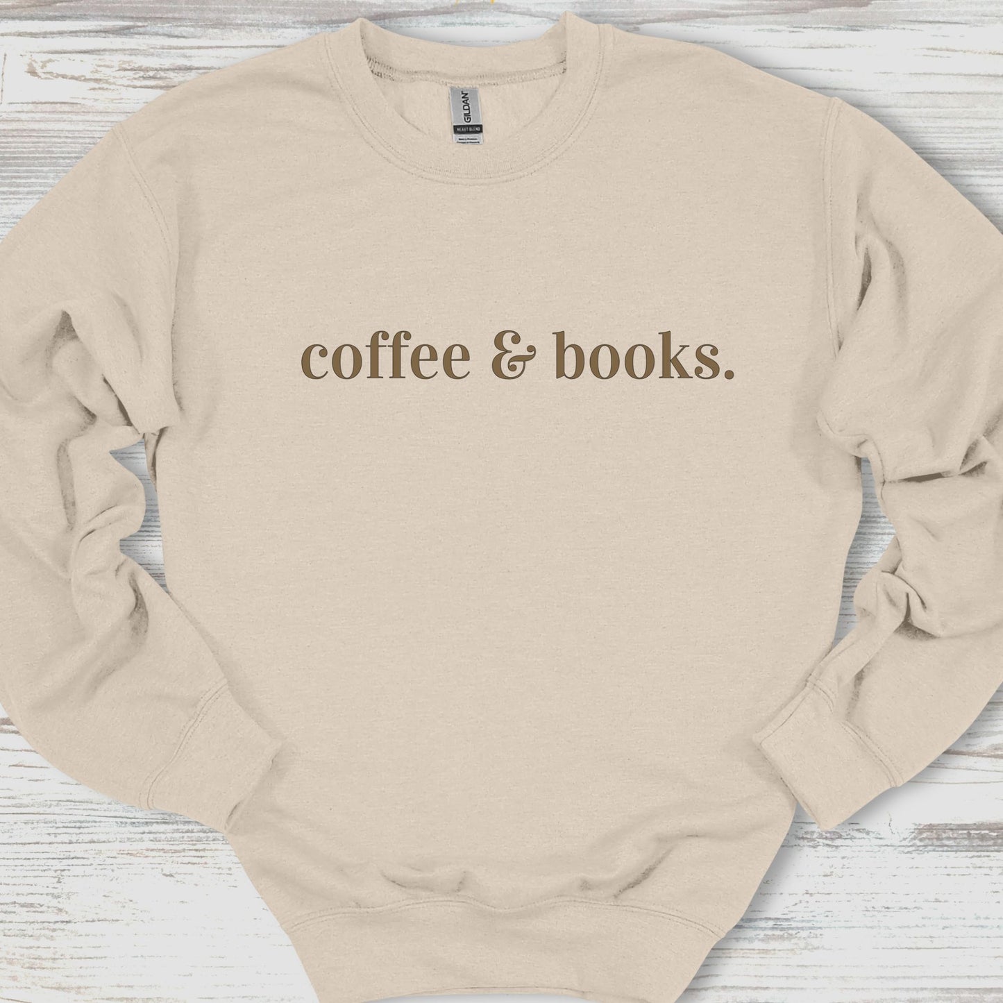 Beige sweatshirt with 'coffee & books.' text on a wooden surface
