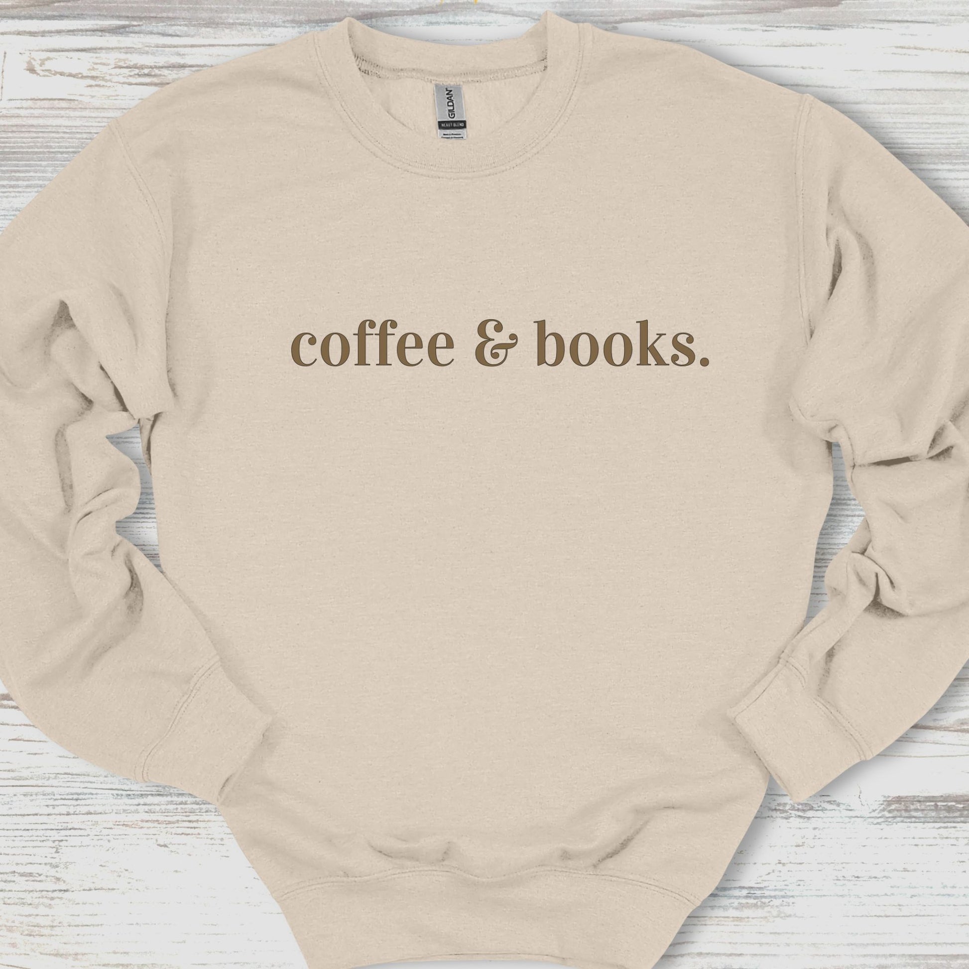 Beige sweatshirt with 'coffee & books.' text on a wooden surface