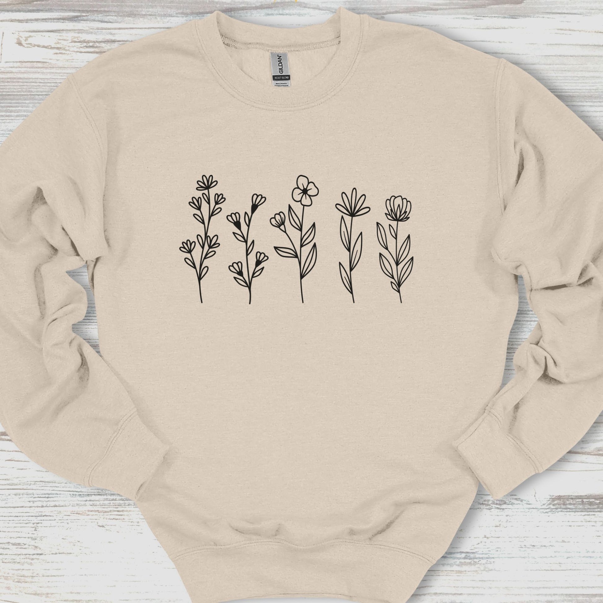 Beige sweatshirt with floral designs on a wooden surface