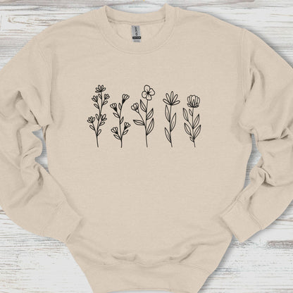 Beige sweatshirt with floral designs on a wooden surface