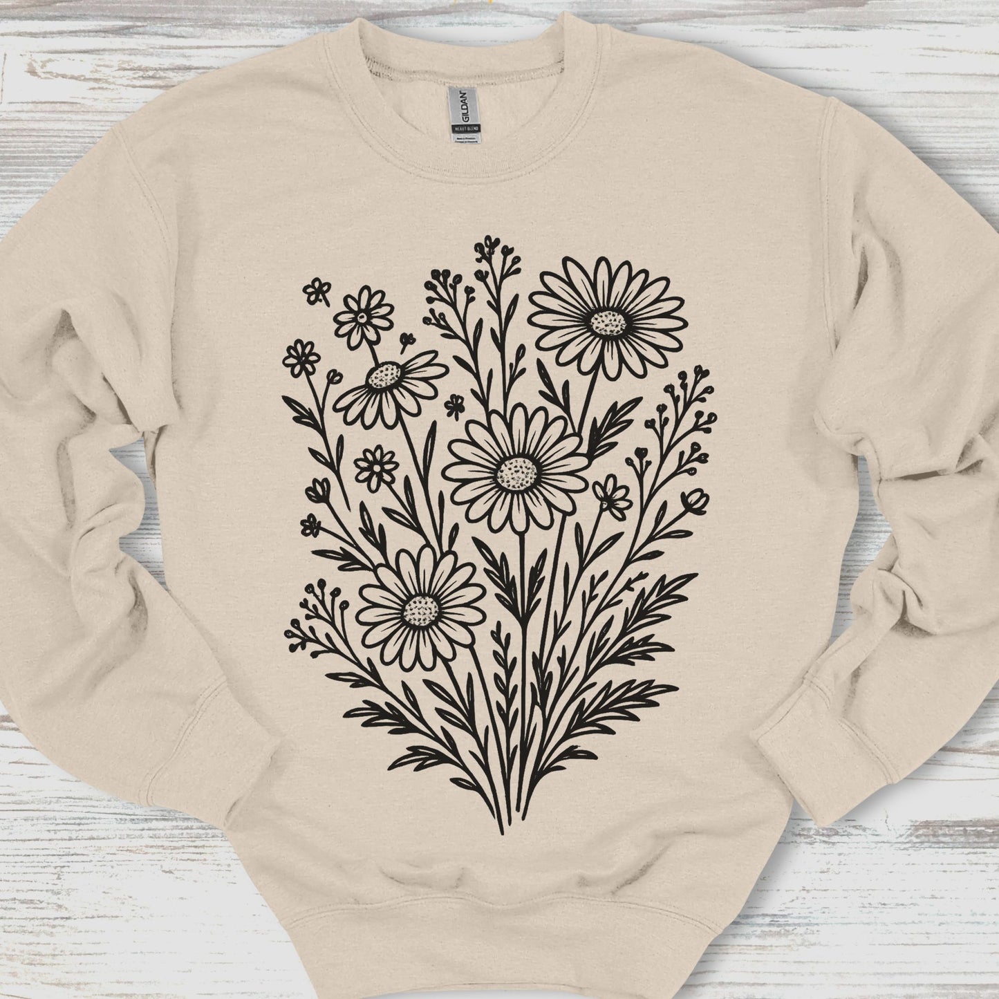 Beige sweatshirt with black floral design on a wooden surface
