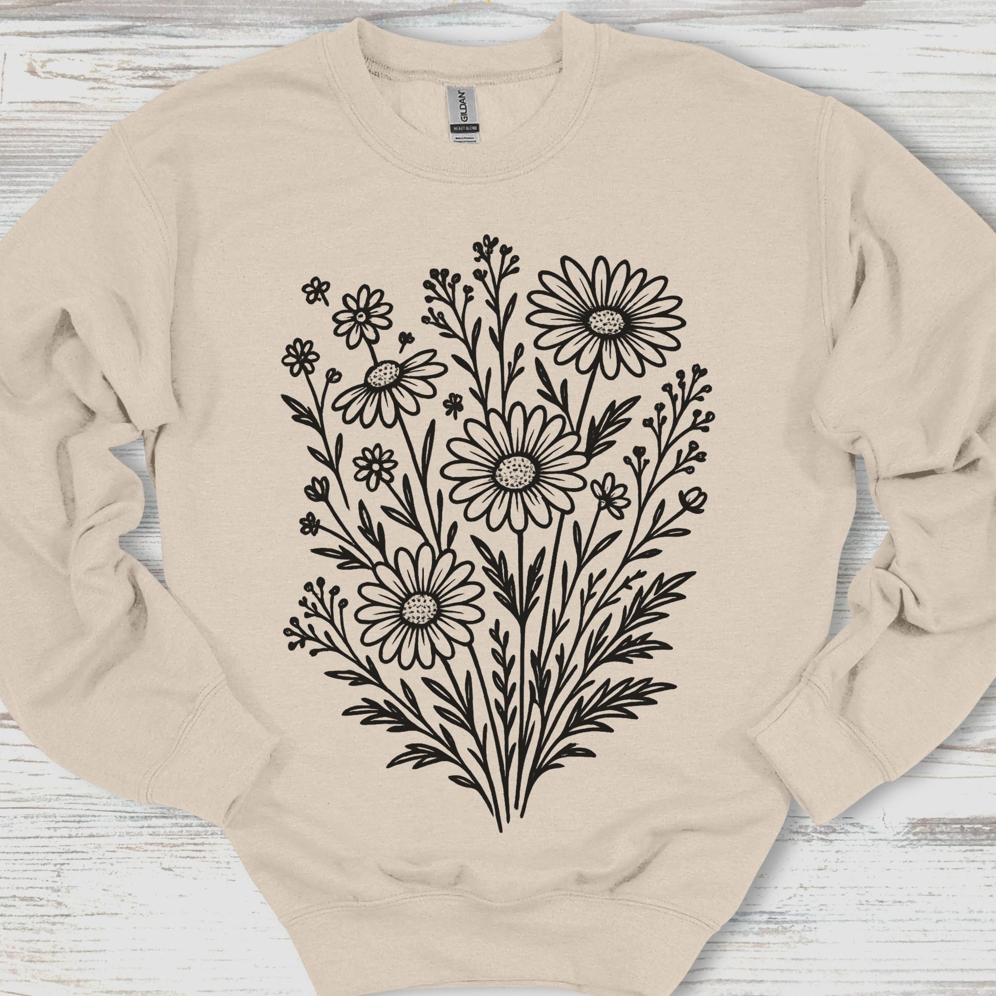 Beige sweatshirt with black floral design on a wooden surface