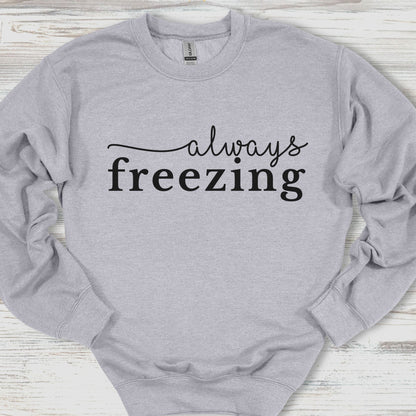 Gray sweatshirt with 'always freezing' text on a wooden surface
