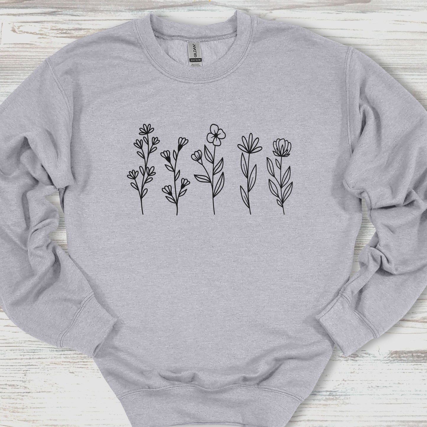 Gray sweatshirt with black floral designs on a wooden surface