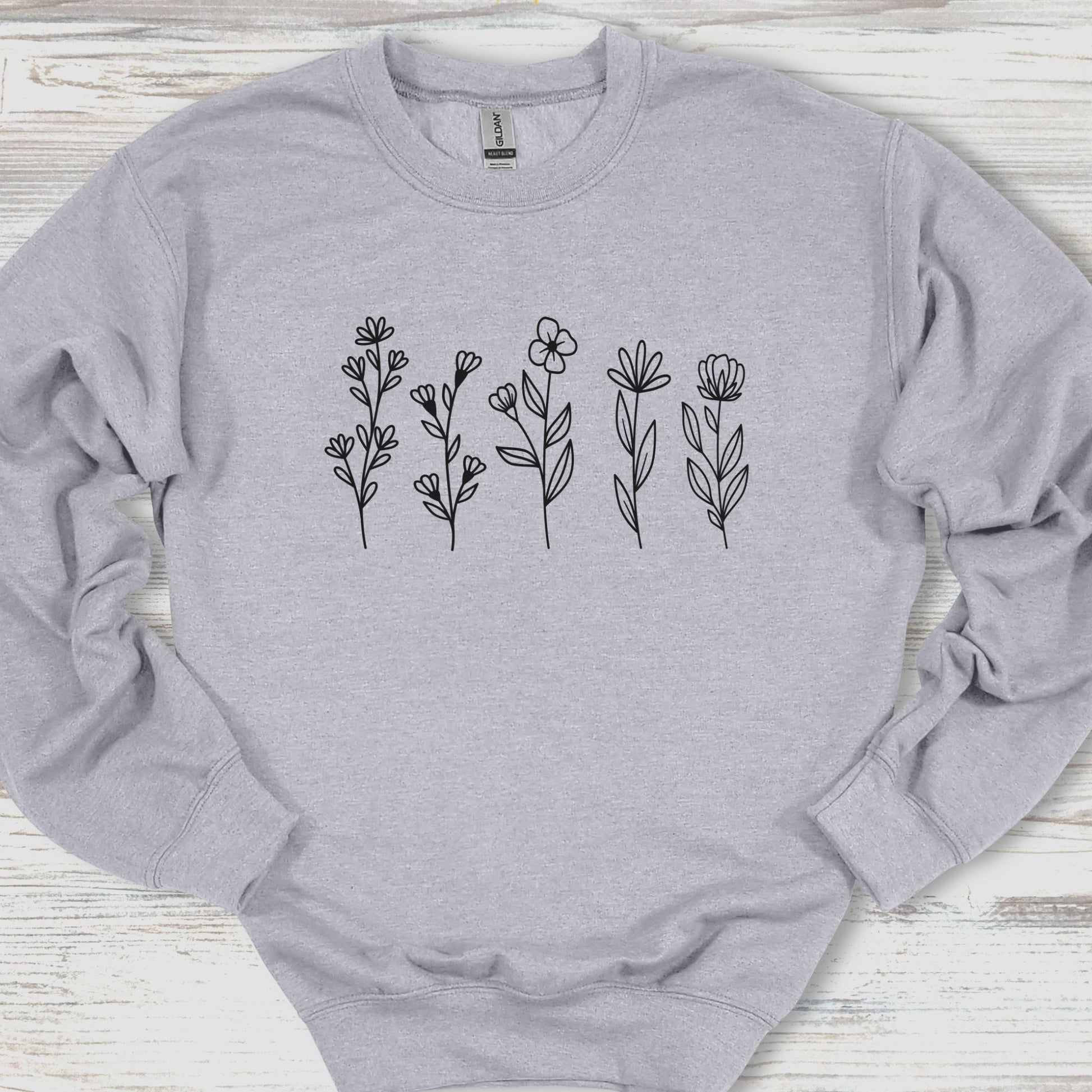 Gray sweatshirt with black floral designs on a wooden surface
