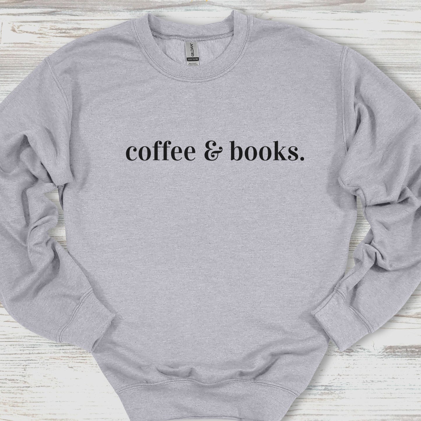 Gray sweatshirt with 'coffee & books.' text on a wooden surface