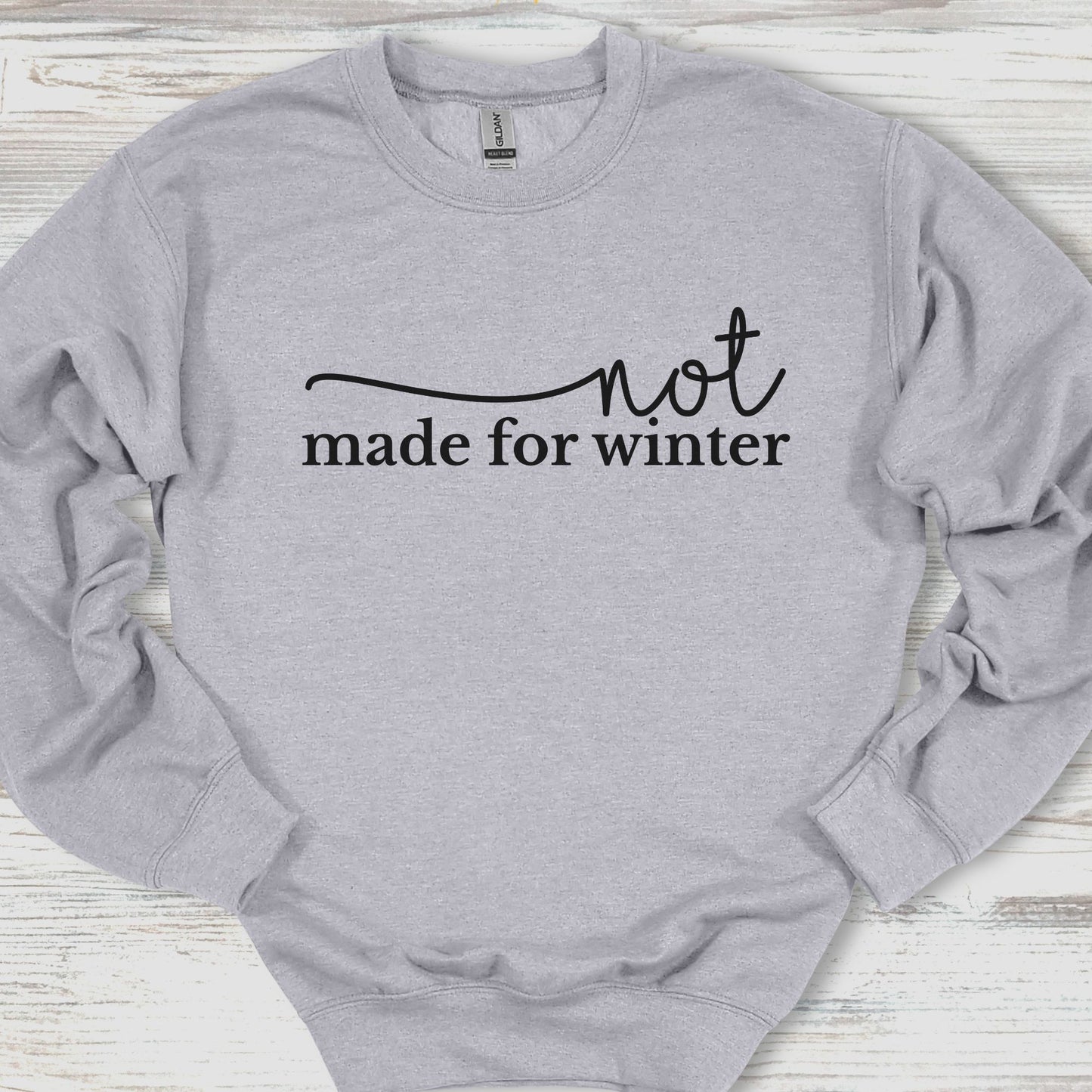 Gray sweatshirt with 'not made for winter' text on a wooden surface