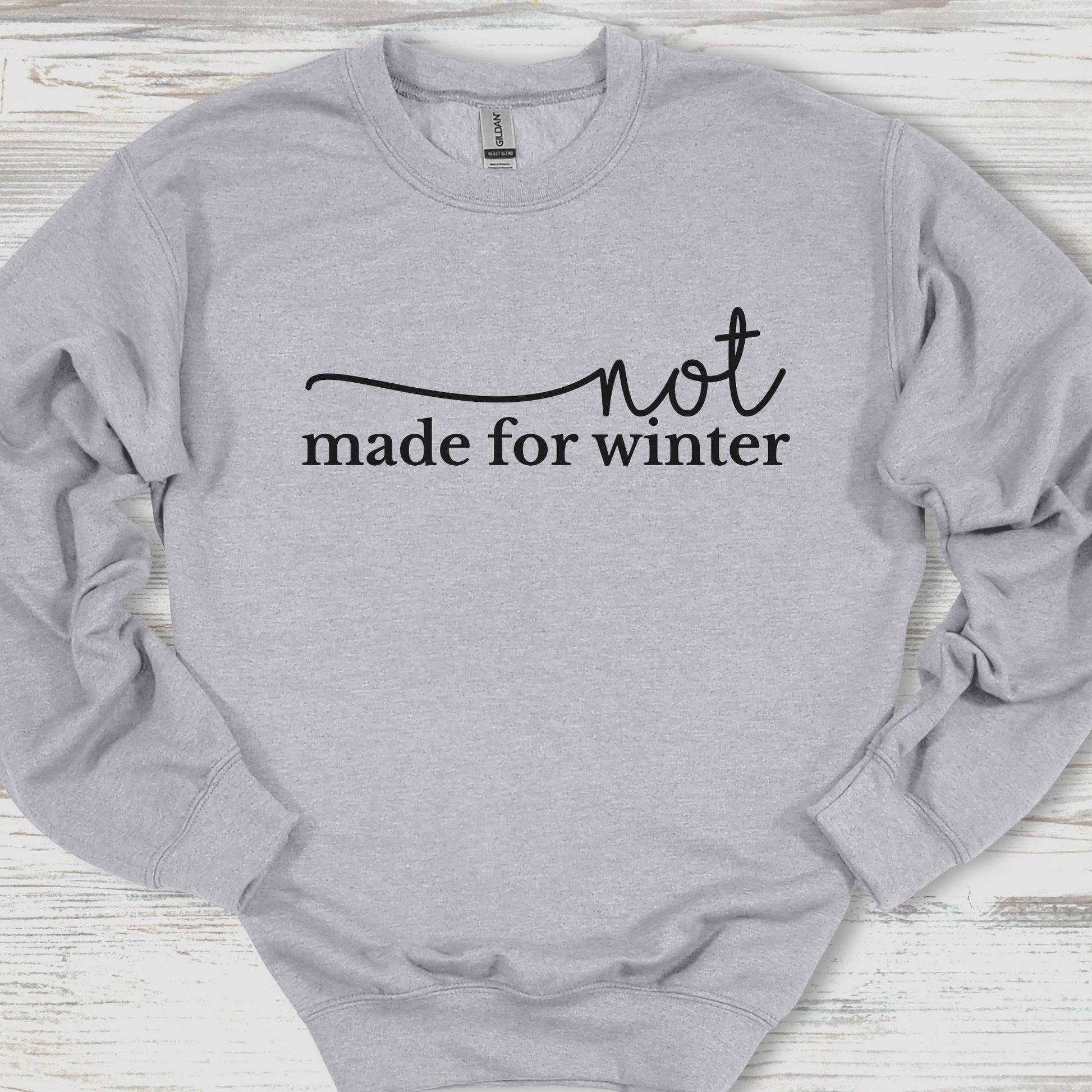 Gray sweatshirt with 'not made for winter' text on a wooden surface