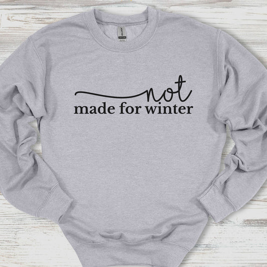 Gray sweatshirt with 'not made for winter' text on a wooden surface