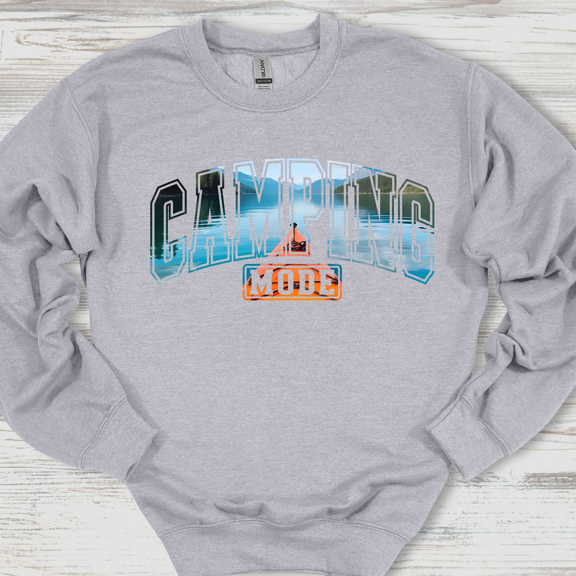 Gray sweatshirt with 'Camping Mode' graphic on a wooden surface