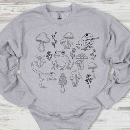 Gray sweatshirt with black line art of frogs and mushrooms on a wooden surface