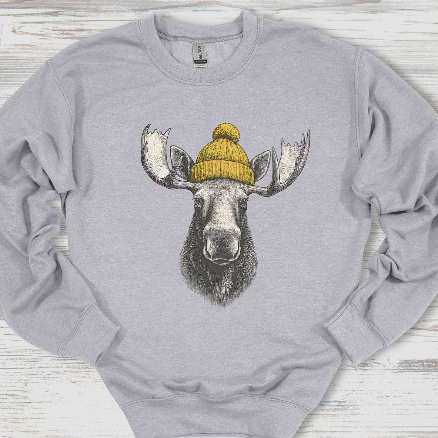 Gray sweatshirt with a moose wearing a yellow beanie on a wooden surface
