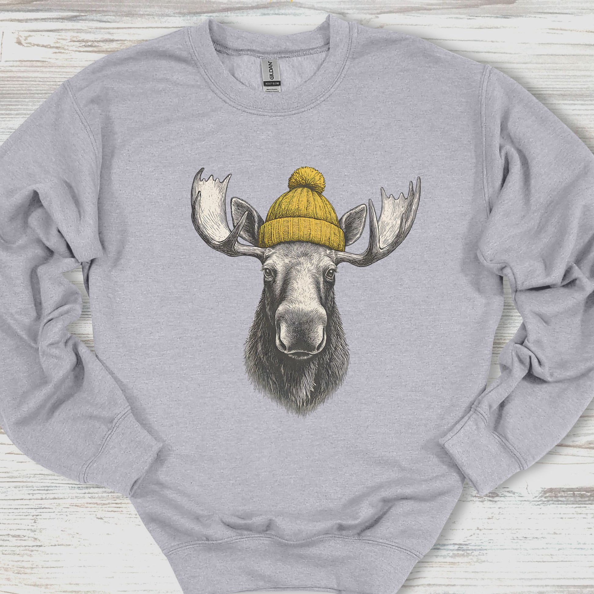 Gray sweatshirt with a moose wearing a yellow beanie on a wooden surface