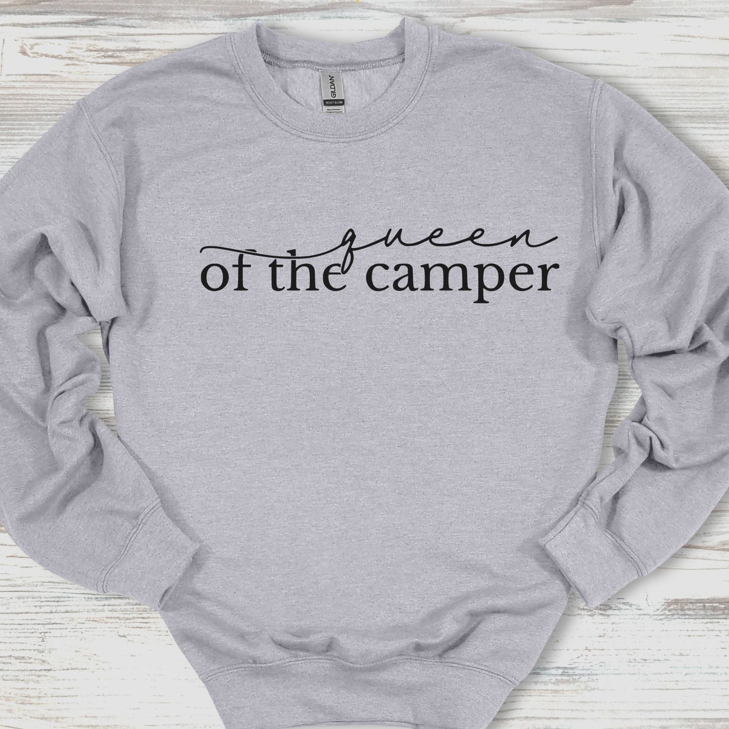 Gray sweatshirt with 'queen of the camper' text on a wooden surface