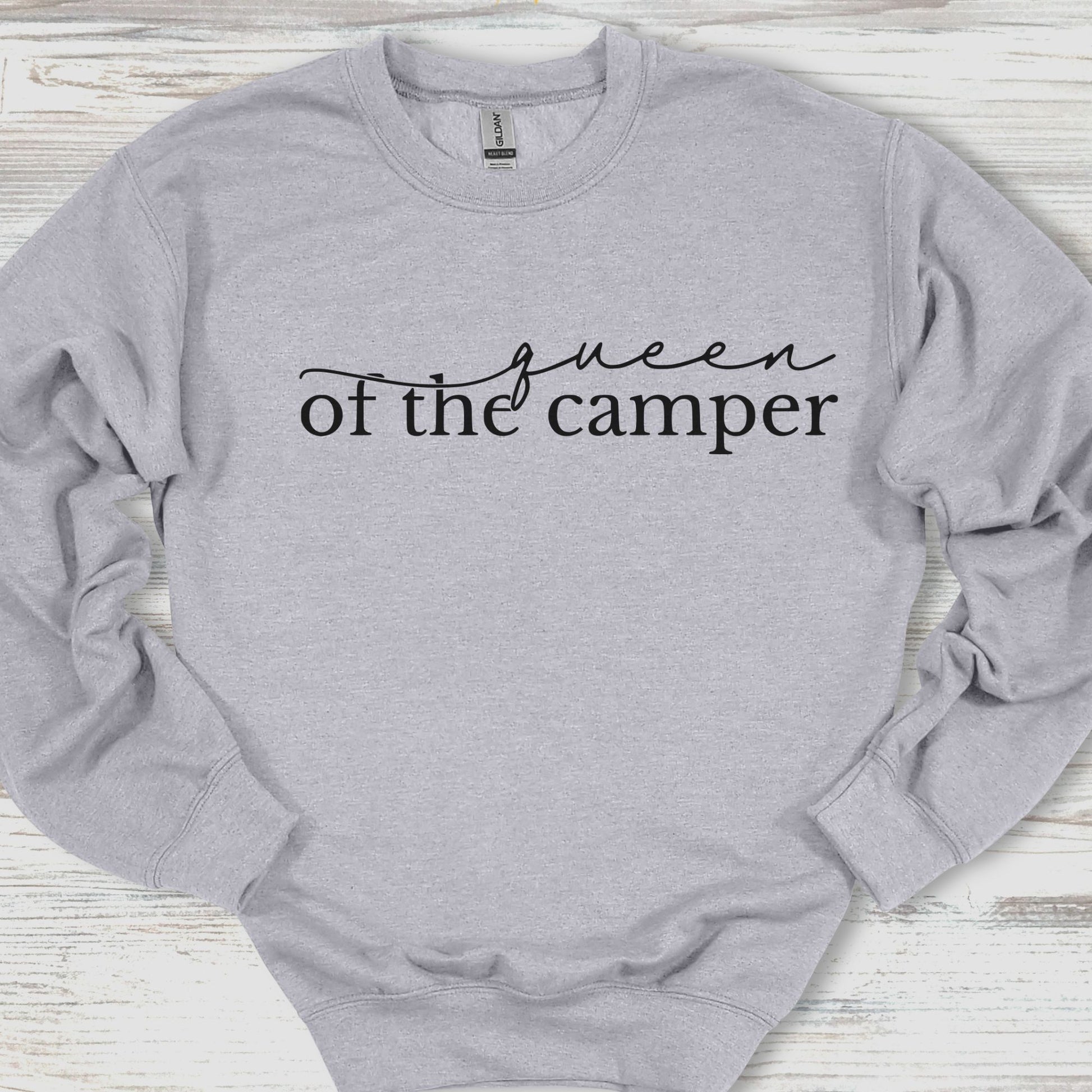 Gray sweatshirt with 'queen of the camper' text on a wooden surface