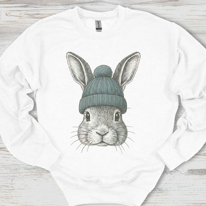 White sweatshirt with a graphic of a rabbit wearing a green beanie on a wooden surface