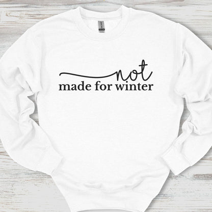 White sweatshirt with 'not made for winter' text on a wooden surface