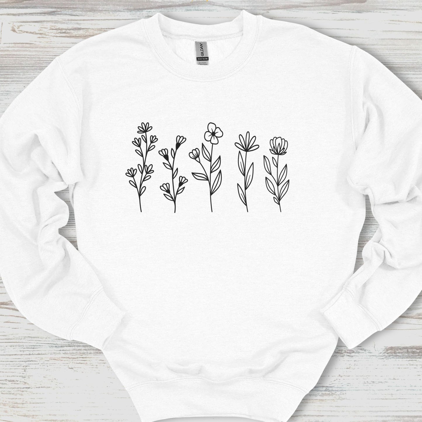 White sweatshirt with black floral patterns on a wooden surface