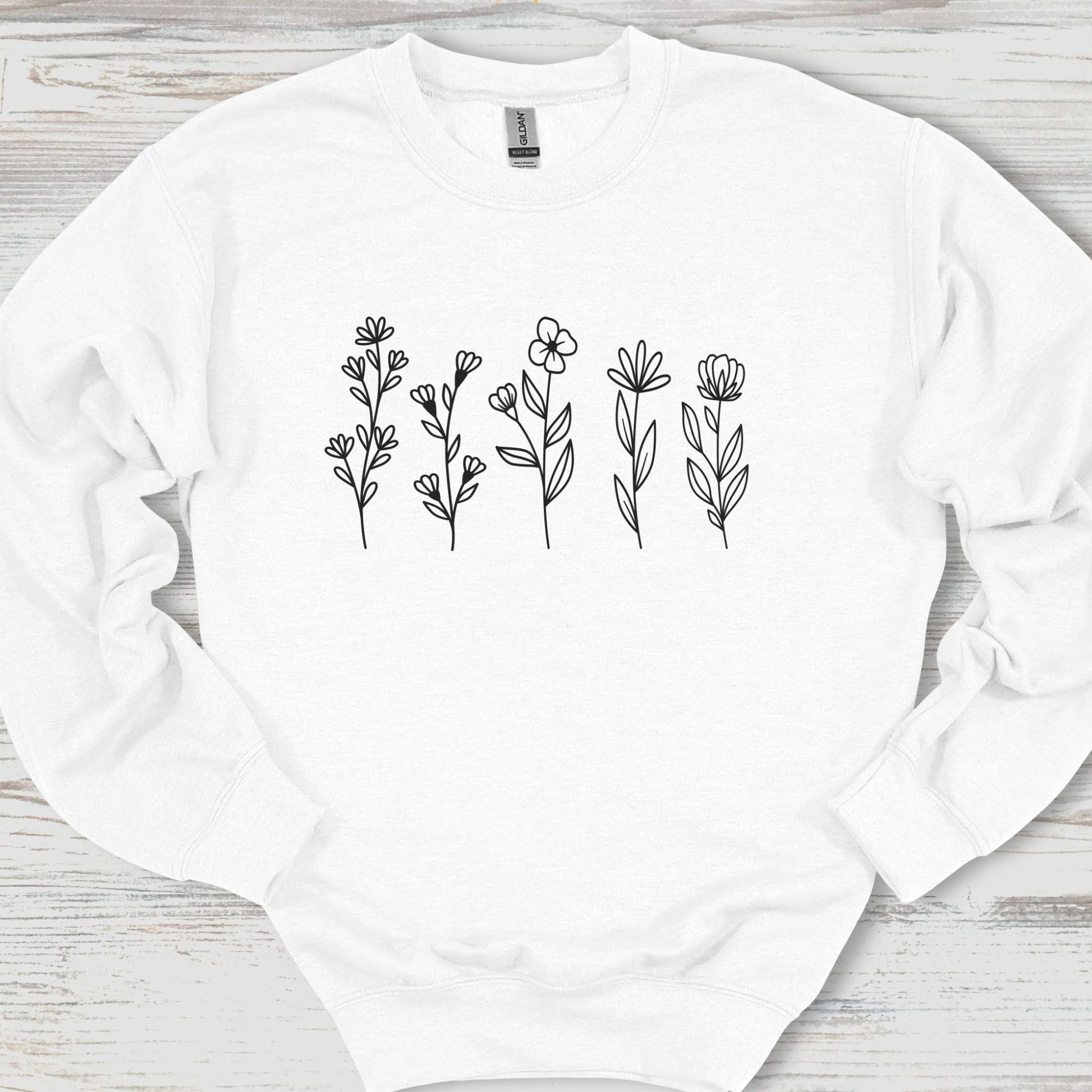 White sweatshirt with black floral patterns on a wooden surface