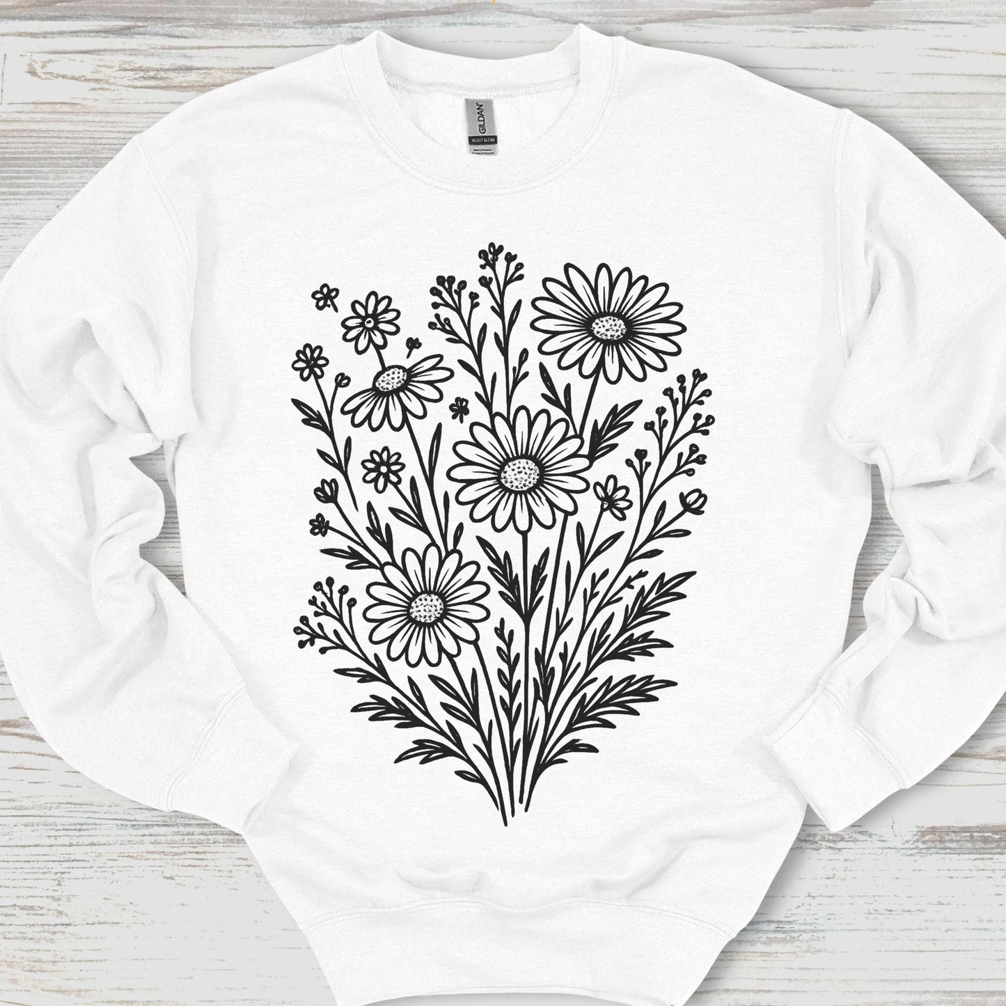 White sweatshirt with black floral design on a wooden surface